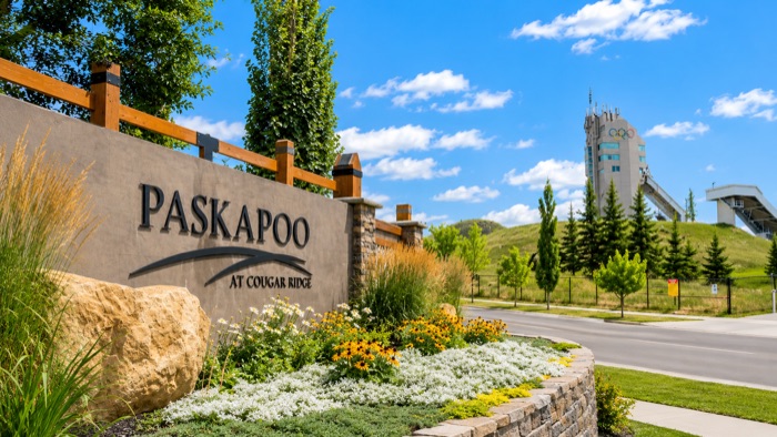 Paskapoo at Cougar Ridge entrance sign with WinSport ski jumps behind